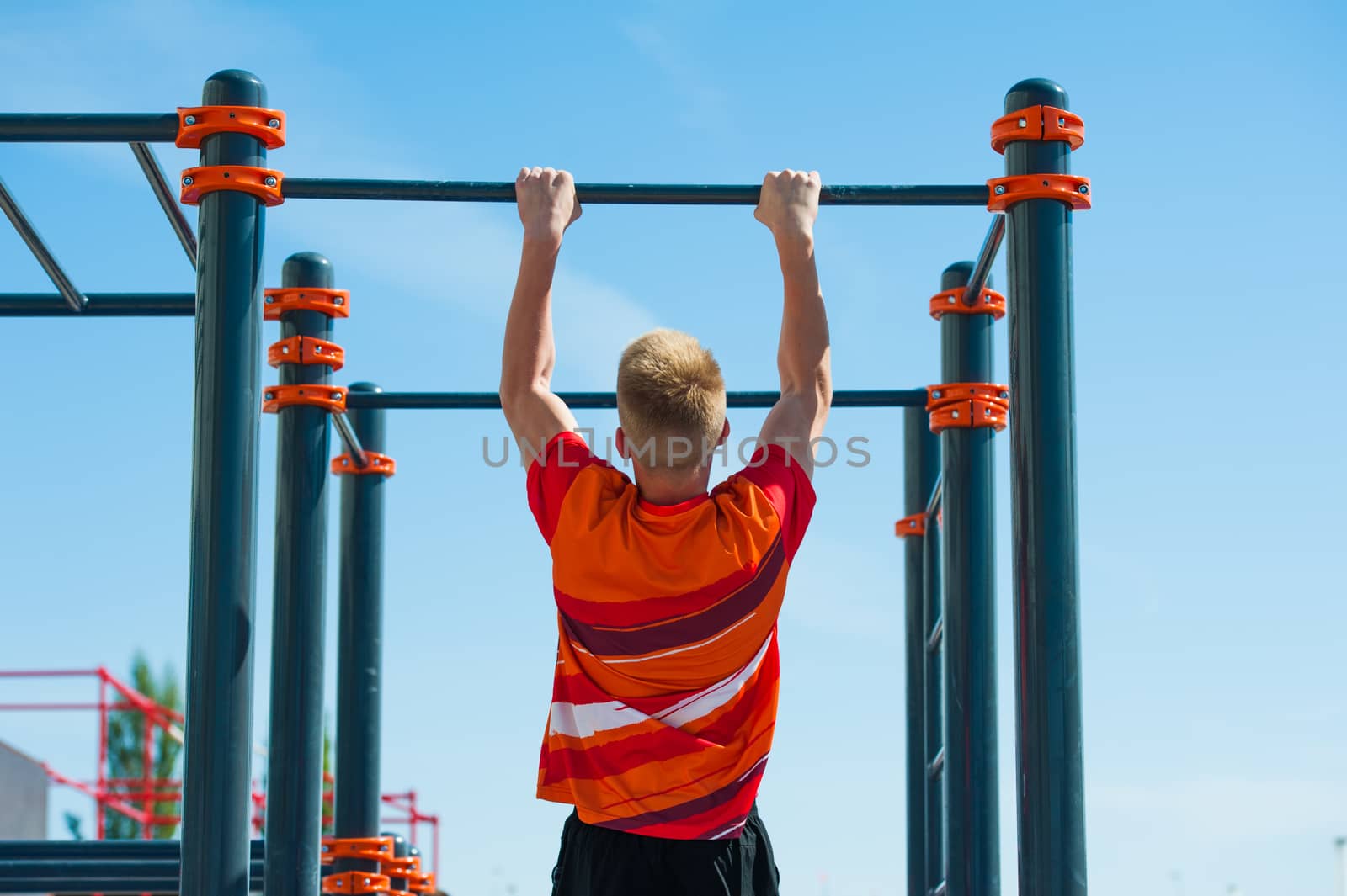 Young man exercising on horizontal bar outdoors. Calisthenics workout.
