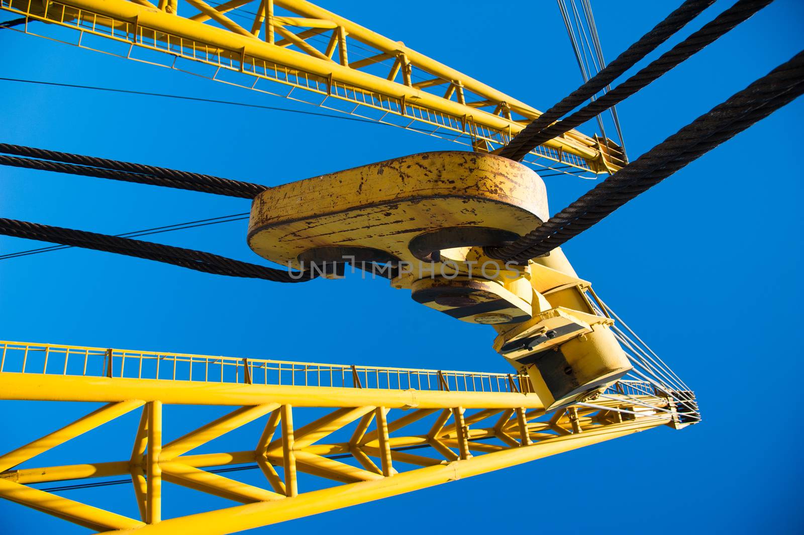 Loading in port. Floating port crane on blue sky background. Chains and hooks hoist with slings for loading in the port close-up