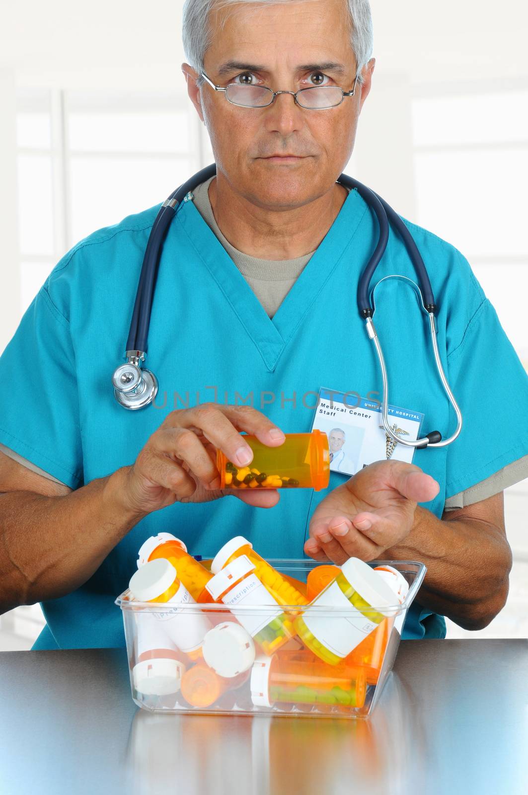 Smiling middle aged doctor pouring prescription medicine from a bottle into his hand. Vertical format in modern office setting.