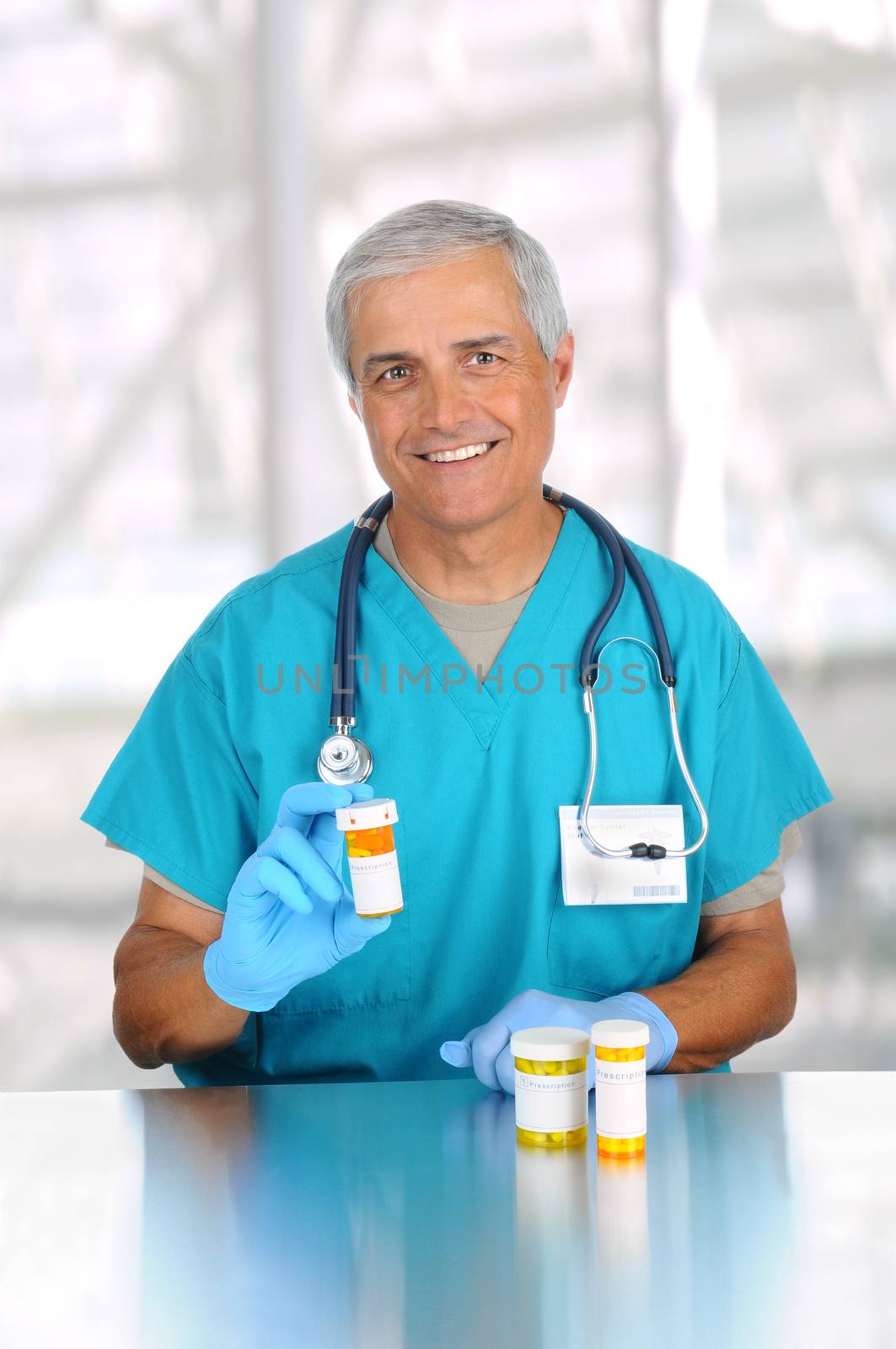 Doctor holding prescription medicine bottle in modern medical facility. Man is wearing scrubs and stethoscope. Vertical format.