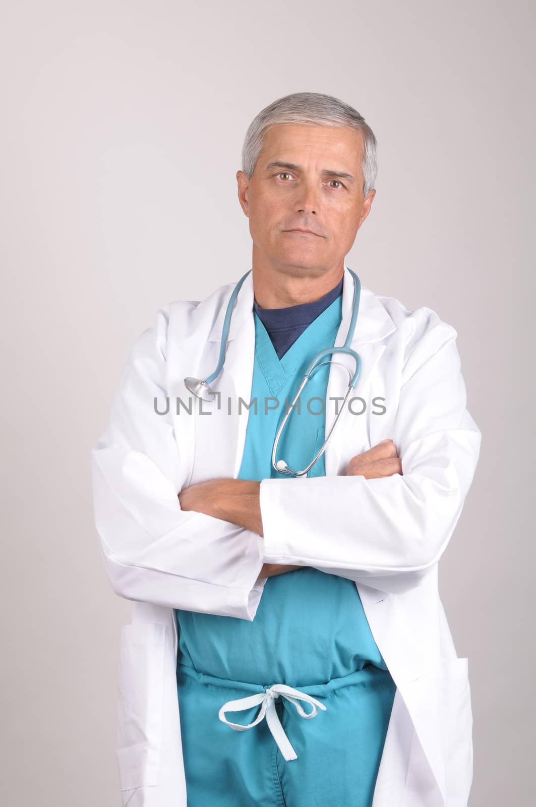 Serious Middle Aged  Doctor in Scrubs and Lab Coat with arms crossed - vertical on gray background