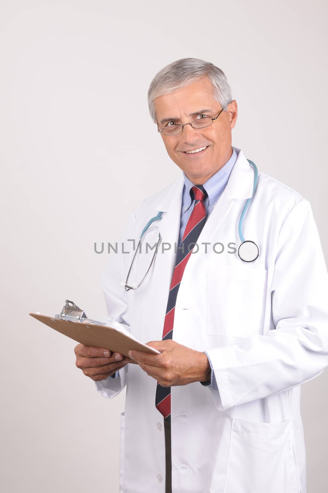 Portrait of a Middle Aged  Male Doctor in Lab Coat with Stethoscope and Clip Board, Vertical Composition on Gray Background