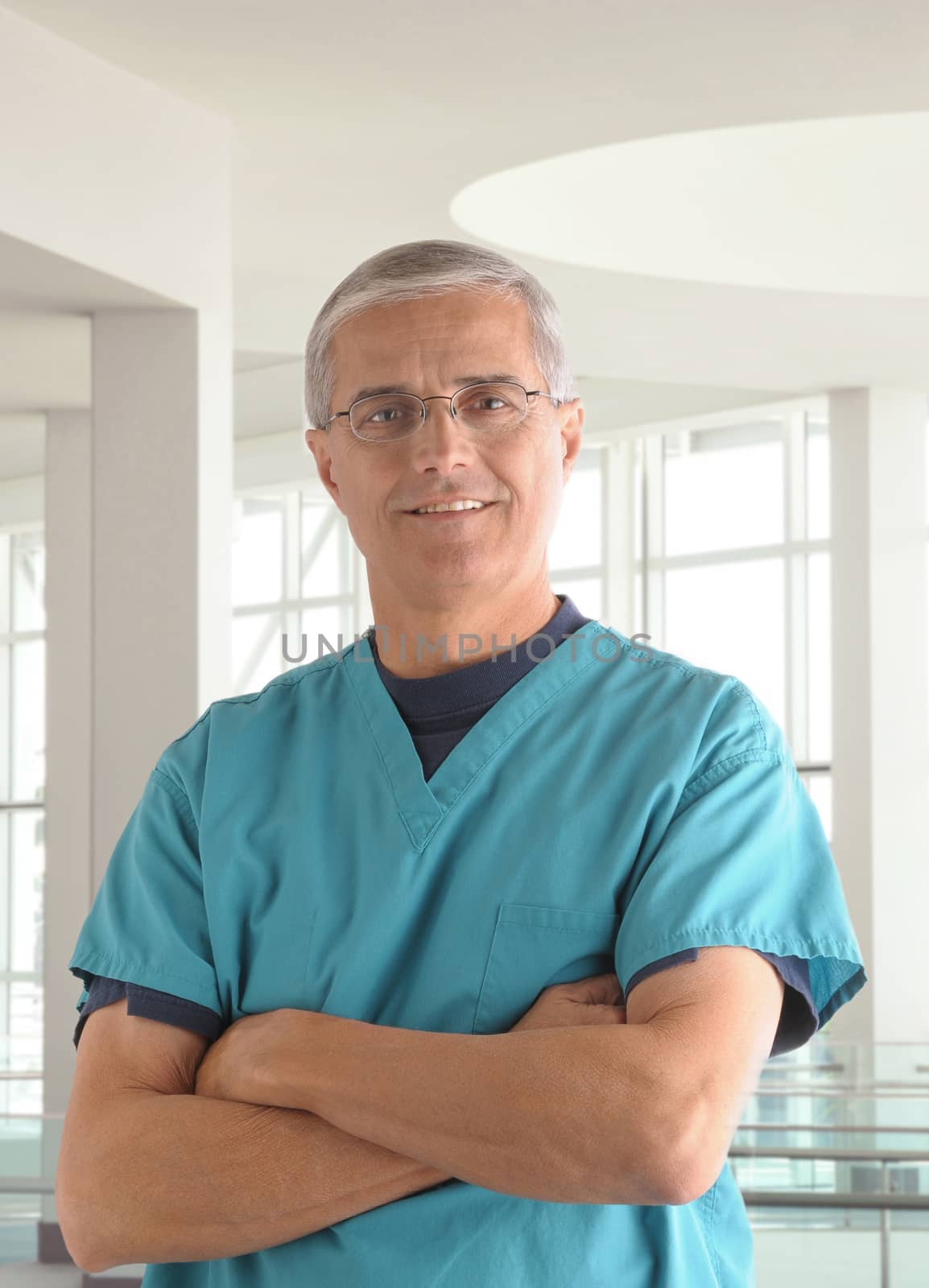 Middle Aged Male Doctor in Scrubs with arms folded in modern office setting vertical format