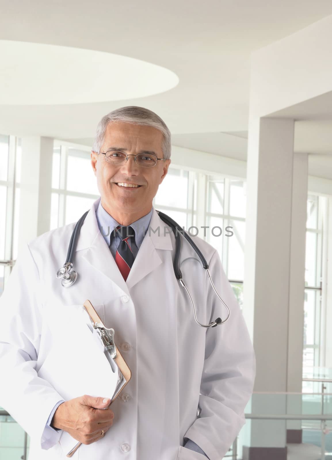 Middle aged doctor wearing lab coat holding a Clip Board in modern medical facility