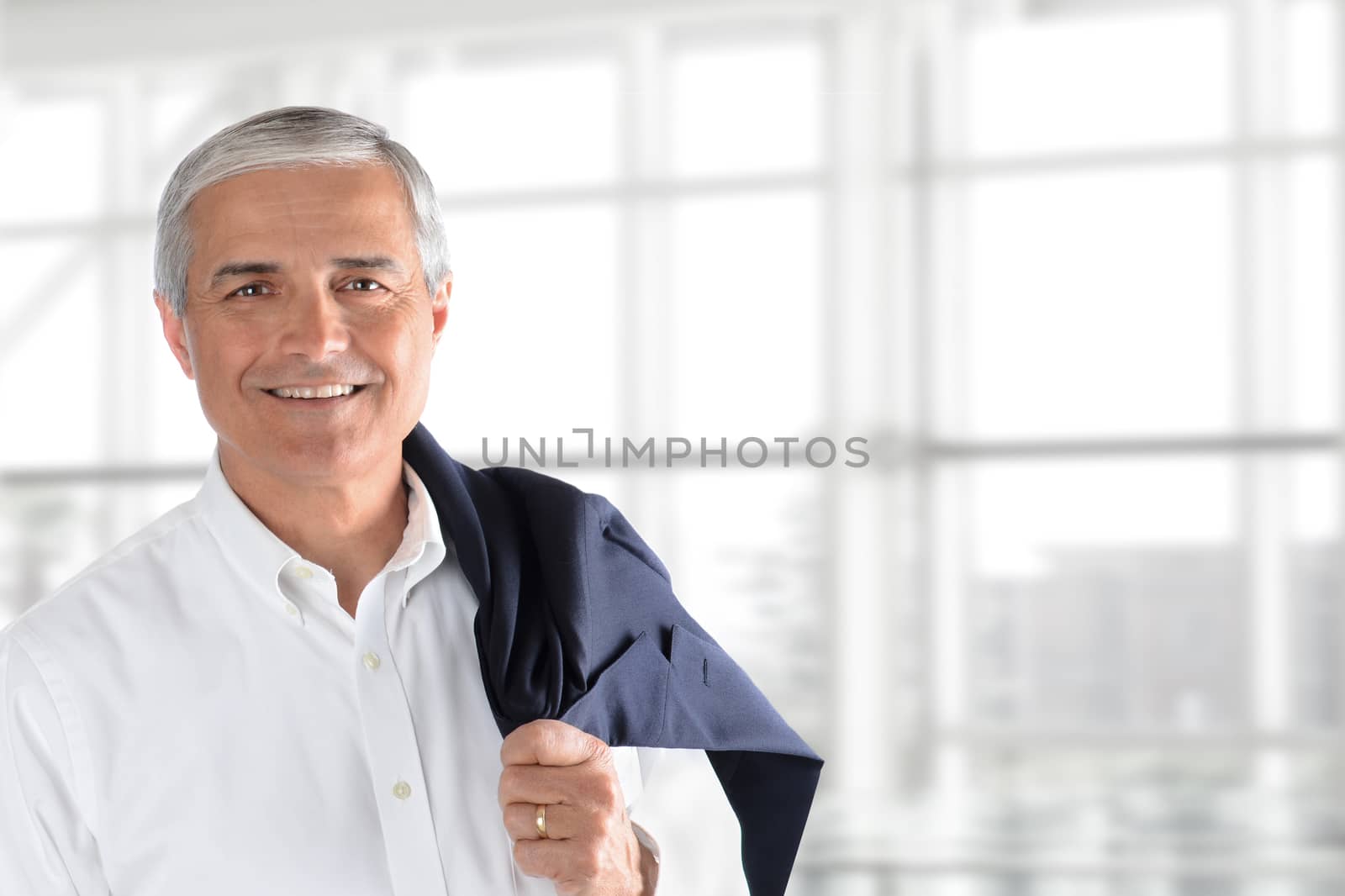 Closeup of a senior businessman holding his jacket over his shoulder in an office interior. Horizontal format with copy space.