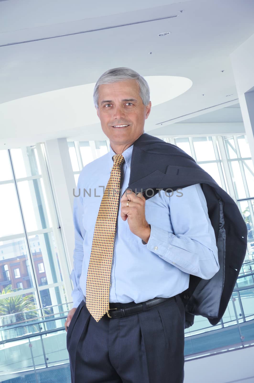 Middle aged Businessman in Lobby with Jacket Over Shoulder by sCukrov