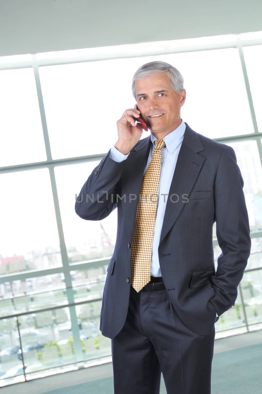 Standing Middle aged Businessman Talking on Cell Phone in Office Setting