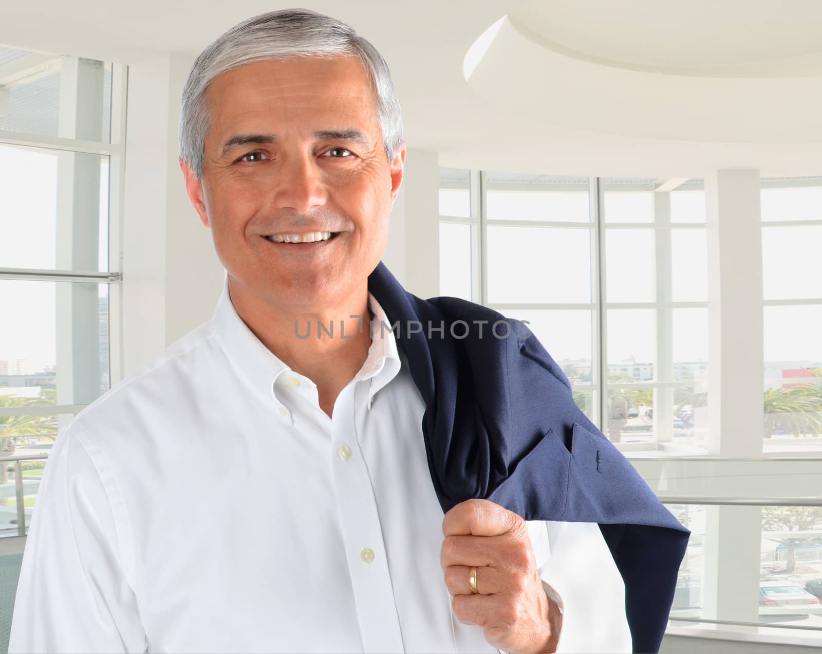 Portrait of a casually dressed businessman in a modern office building. Man is smiling holding his jacket over his shoulder.