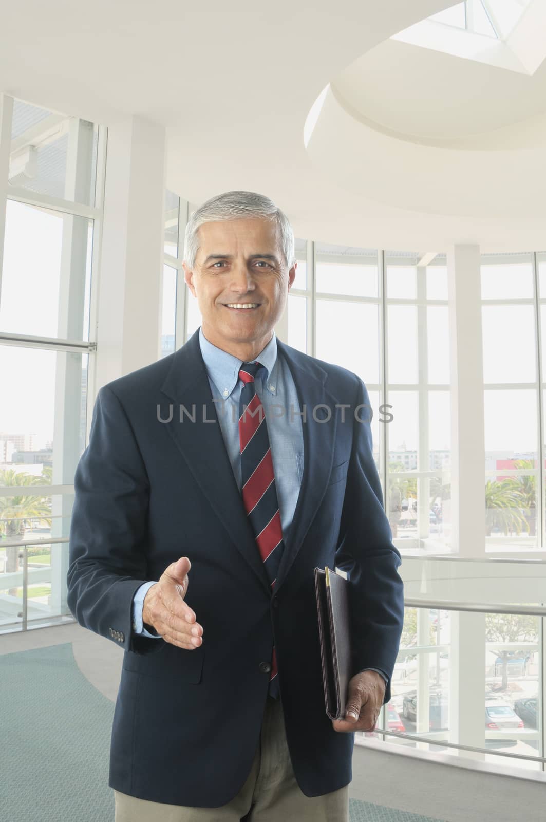 Middle Aged Businessman in Blue Blazer and Khaki Trousers with hand extended to shake vertical format