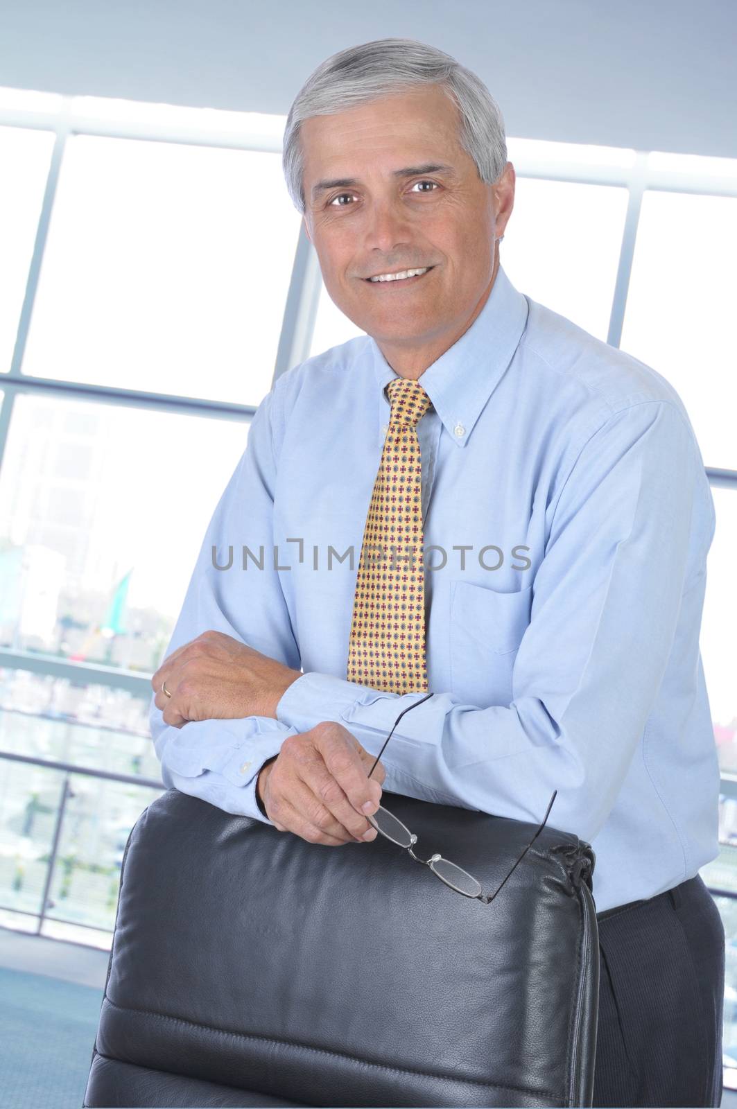Middle aged Businessman leaning on the back of his chair in office setting