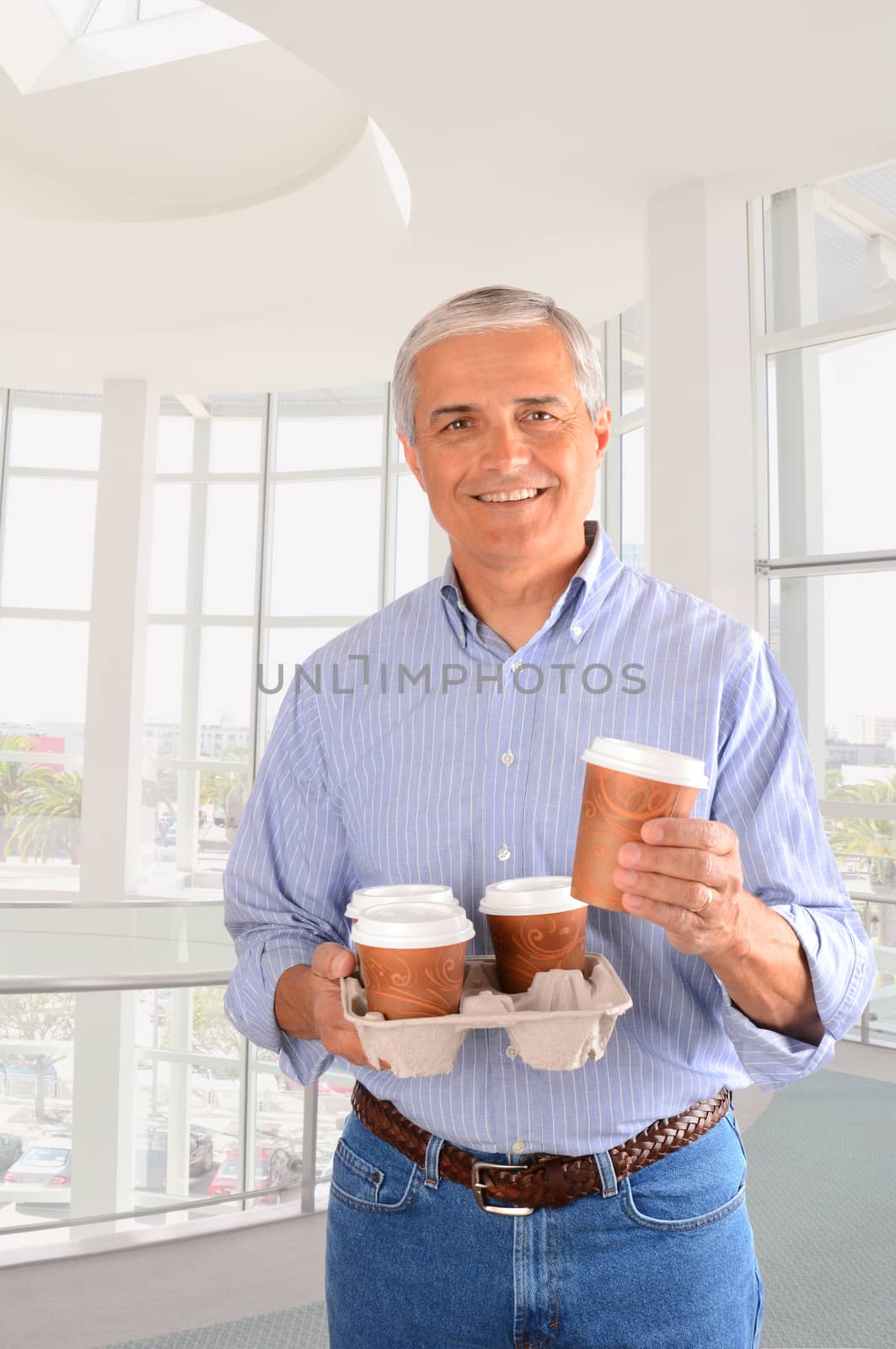 Closeup of a smiling middle aged businessman bring coffee for the office. Vertical Format