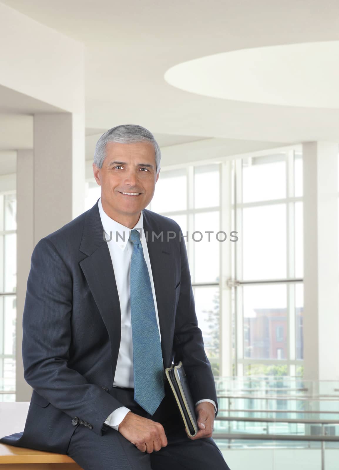 Middle Aged Businessman Sitting on Desk by sCukrov