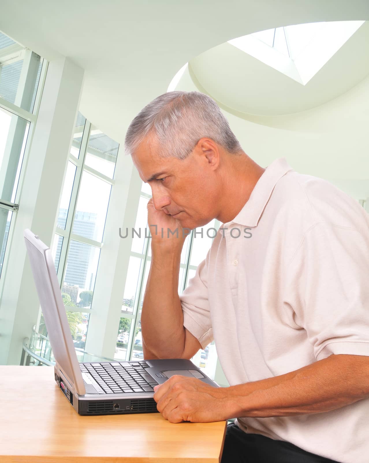 Middle aged Man Looking Intently at Laptop side view in office setting