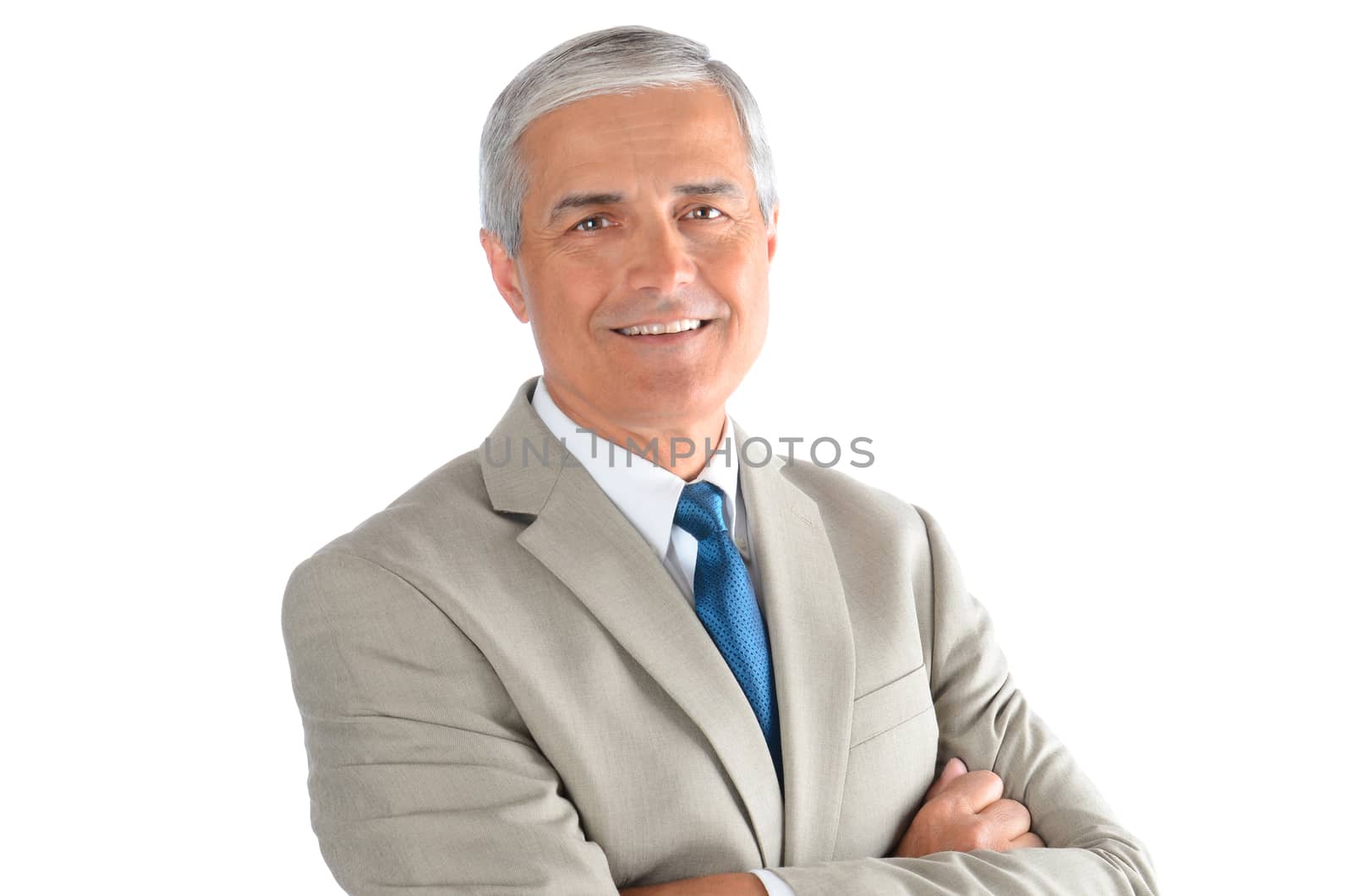 Portrait of a smiling middle aged businessman wearing a light tan suit with a blue necktie and his arms crossed. Horizontal over a white background.