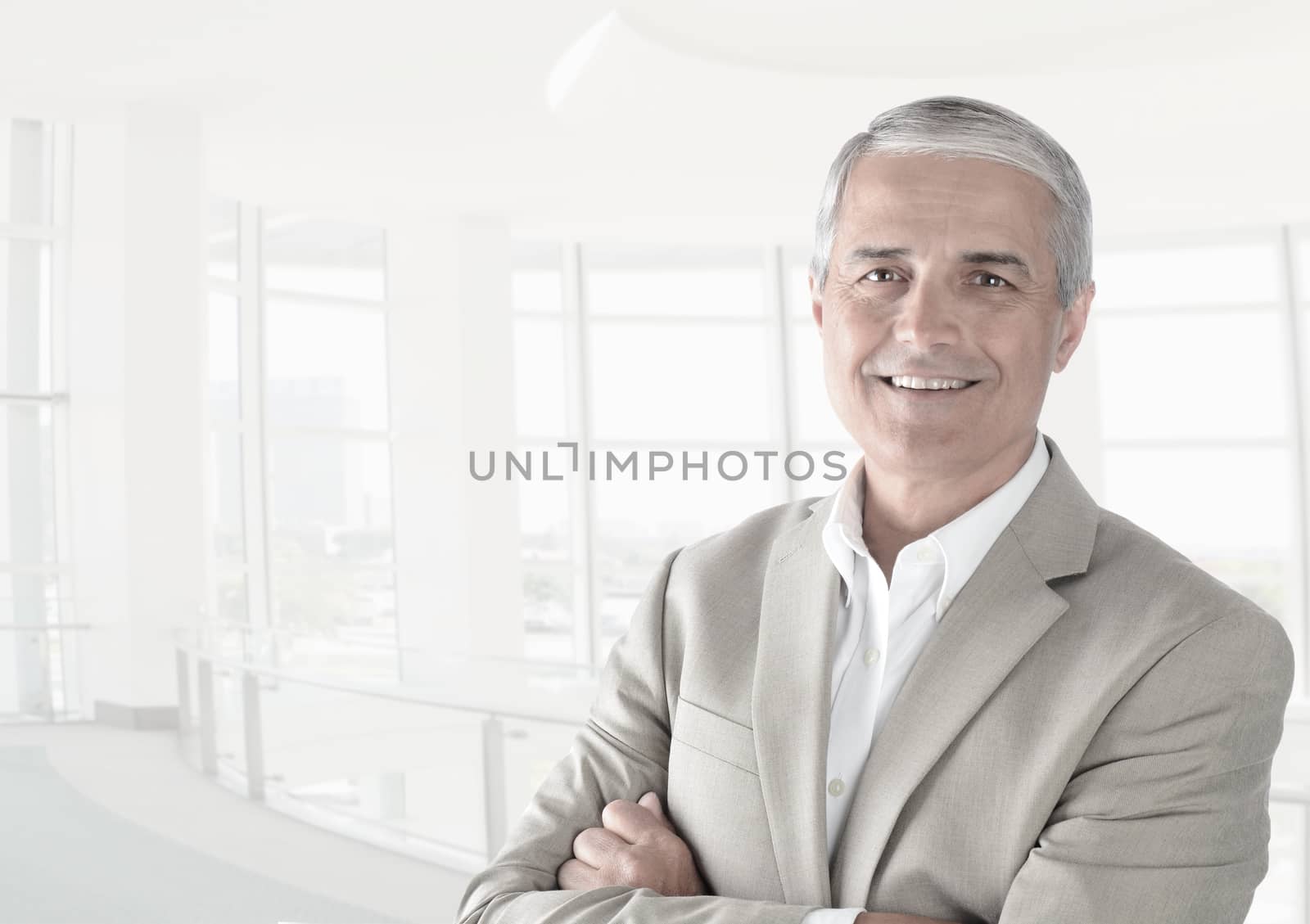 Casual businessman in a modern office with his arms folded. Horizontal format in high key. 