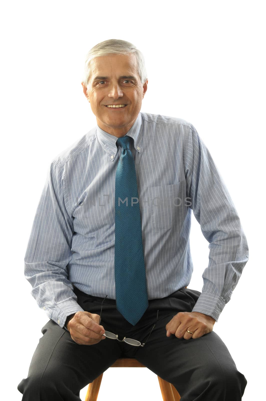 Businessman sitting on a stool holding his eye glasses isolated on white background vertical format