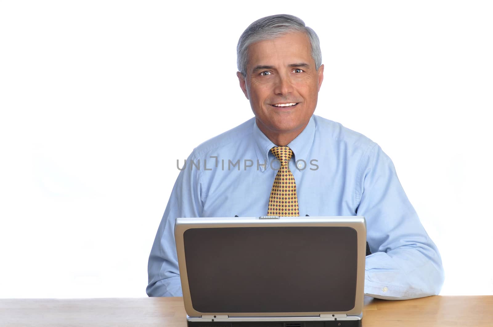 Smiling Businessman at desk with Laptop Computer isolated on white