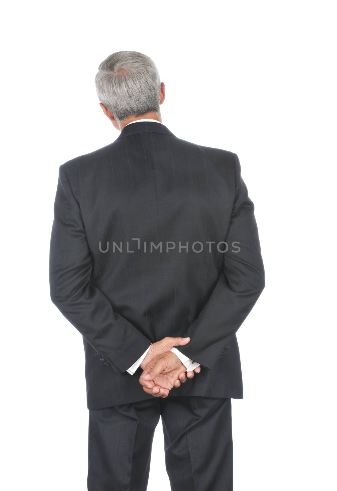 Middle aged businessman with his hands behind back Head tilted to one side isolated over white
