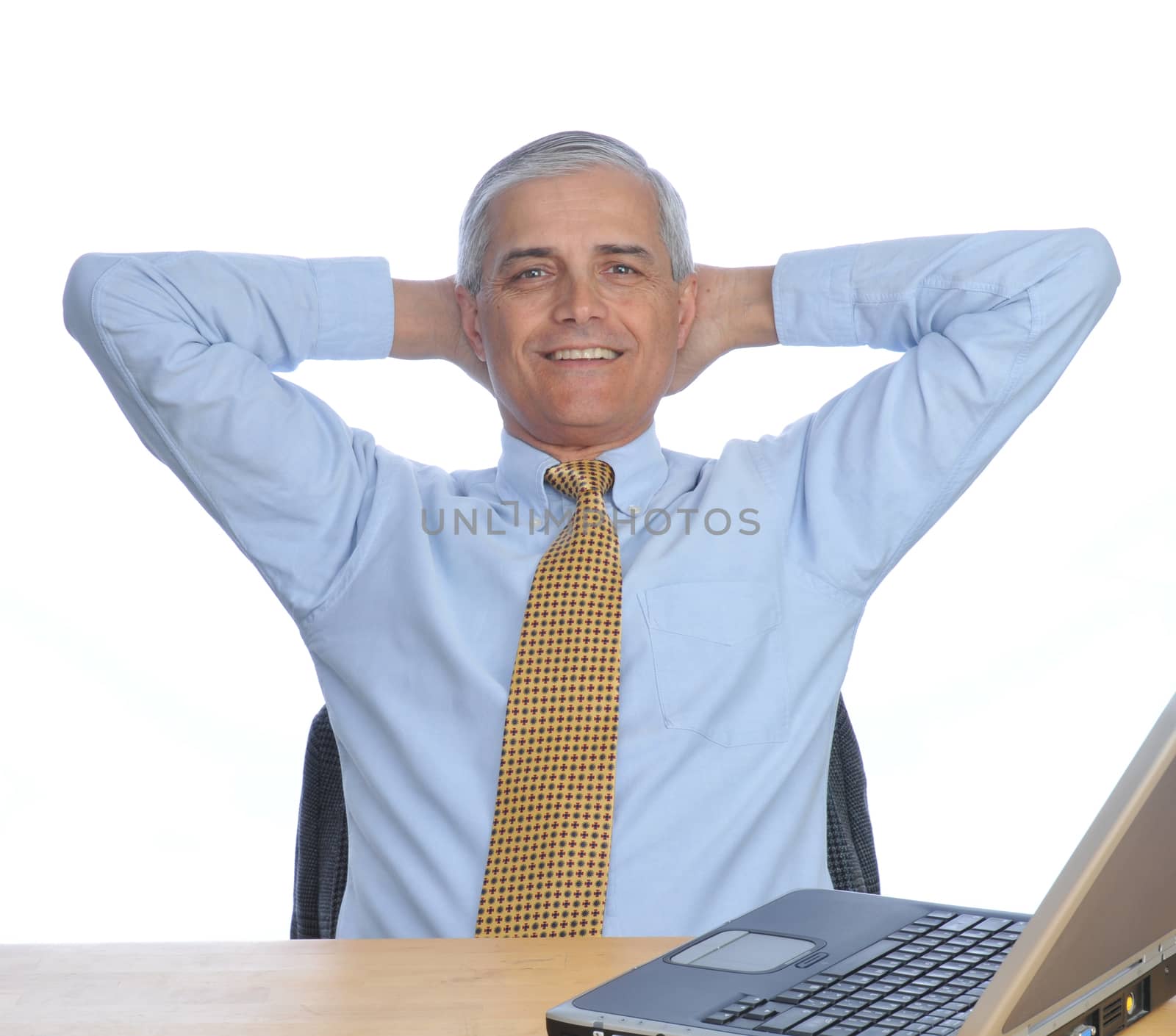 Businessman Siting at His Desk with hands behind his head