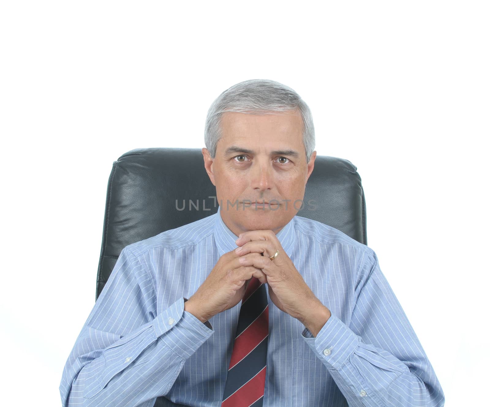 Middle aged businessman sitting at his desk with hands clasped under chin isolated over white 