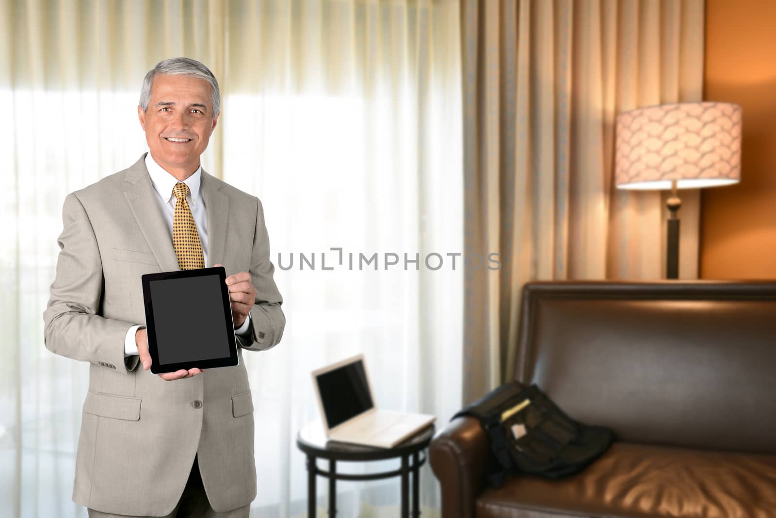 Businessman in hotel room with tablet computer. Business travel concept.