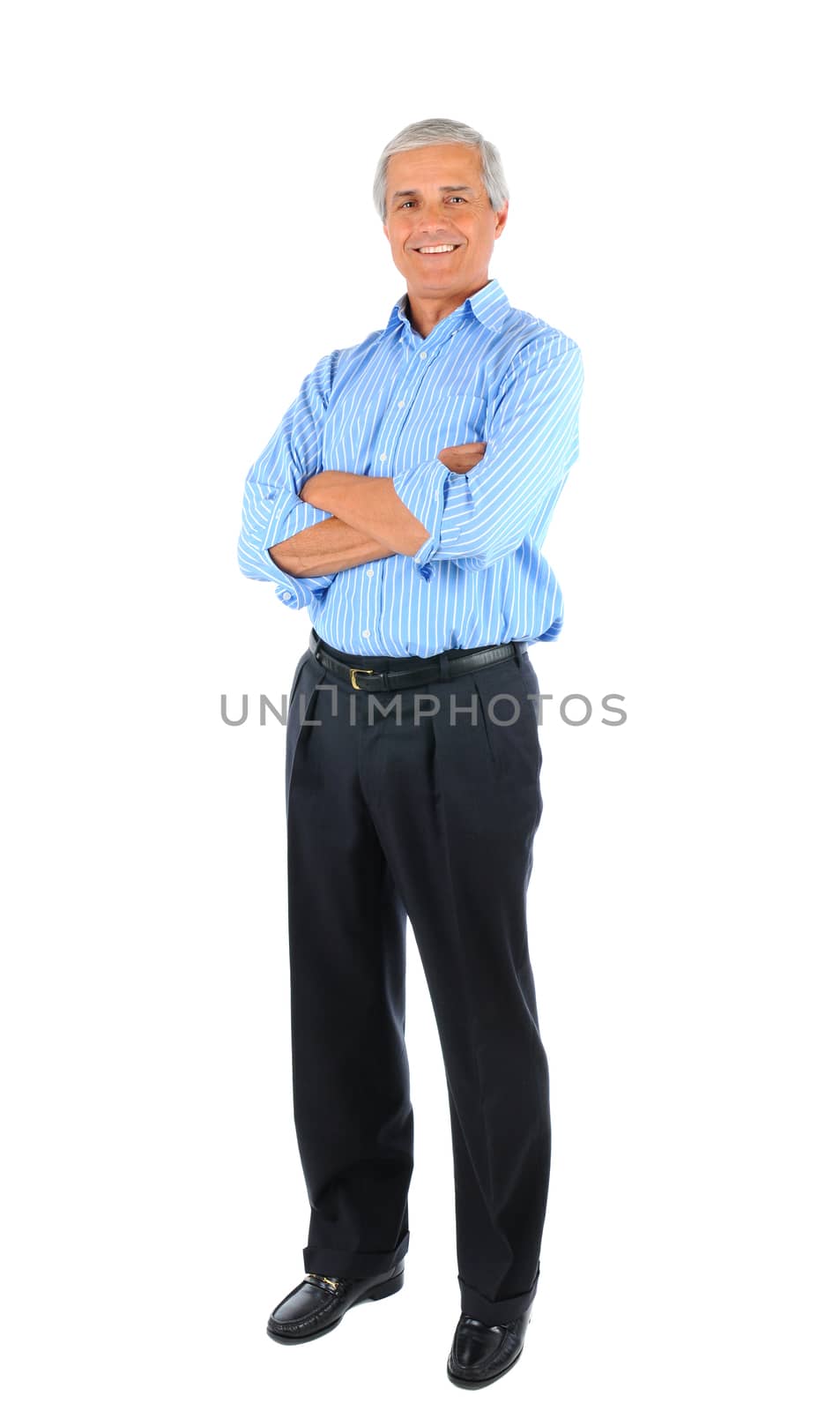 Smiling middle aged businessman standing with his arms folded. Full length over a white background.