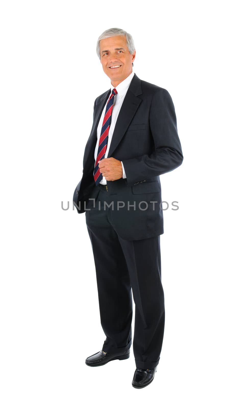 Smiling middle aged businessman in a suit and tie standing with one hand in his pocket. Full length over a white background.