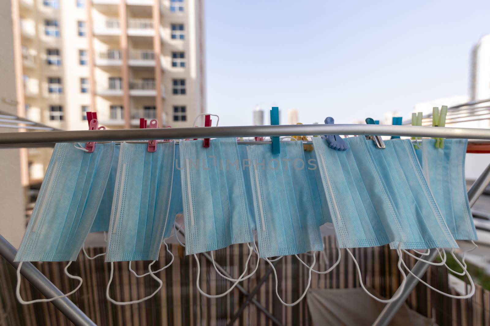 Blue disposable surgical mask washed and hanging on a drying rack. Concept of shortage of personal protection equipment (PPE). Concept of re usability and recycling during crisis times. by dugulan