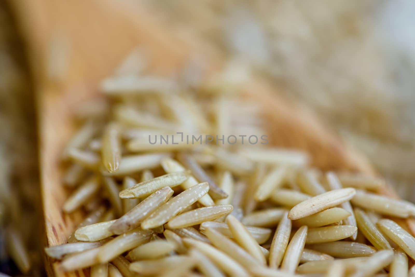Macro close-up of brown rice on wooden spoon. Creative food concept.