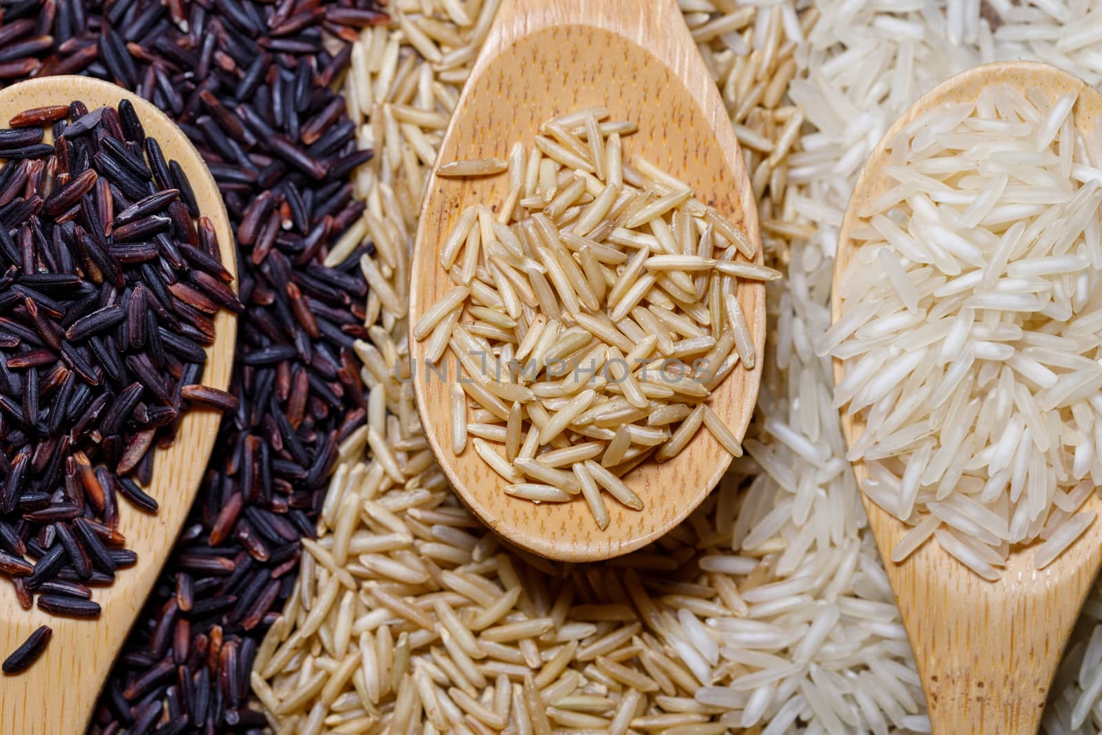 Black wild rice, brown wild rice and white jasmine rice in wooden spoon flat lay. Creative layout. Food concept