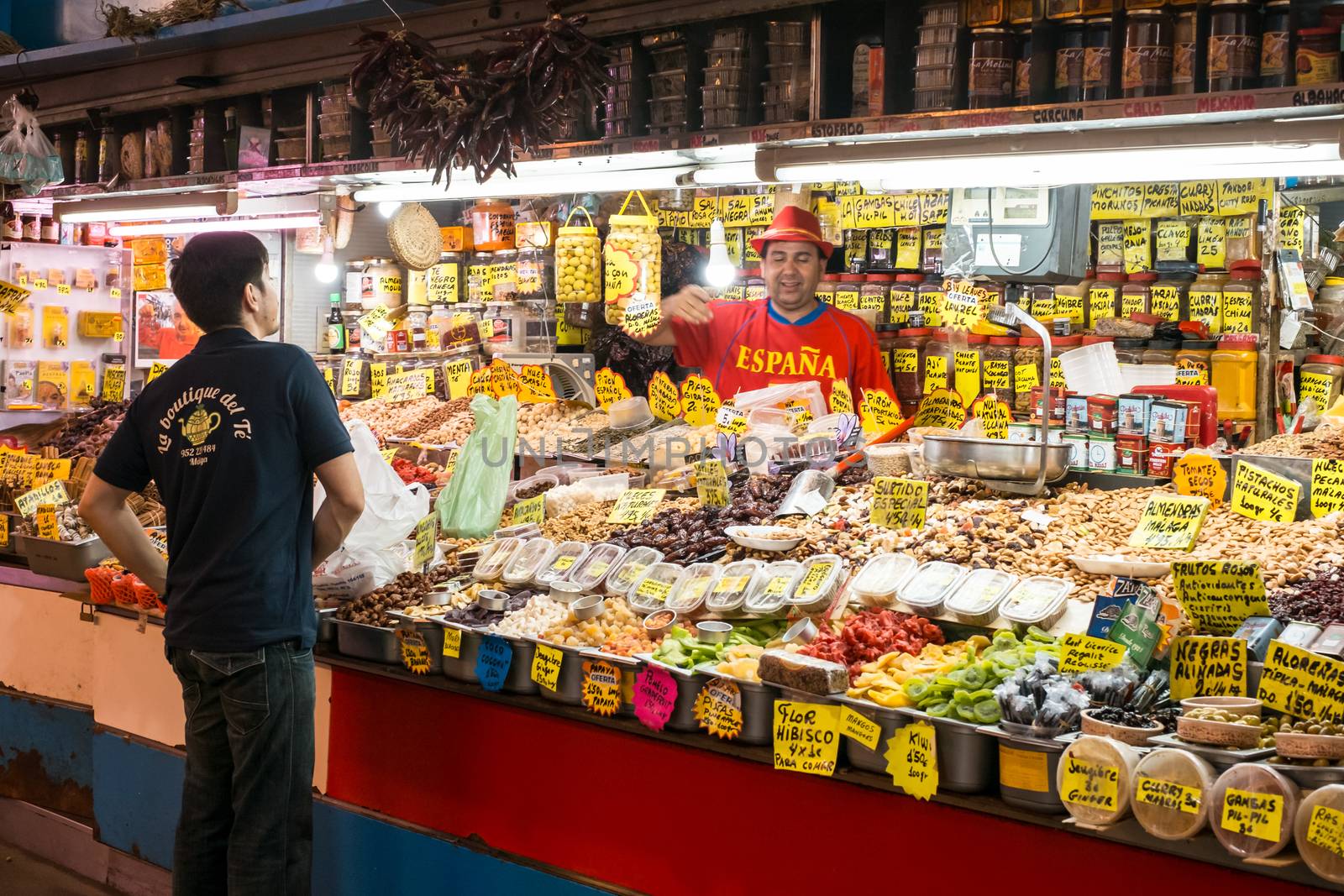 Malaga, Spain - May 05, 2018. A man sells dried fruits and vegetable stall at Ataranzanas Central Market, Malaga, Spain