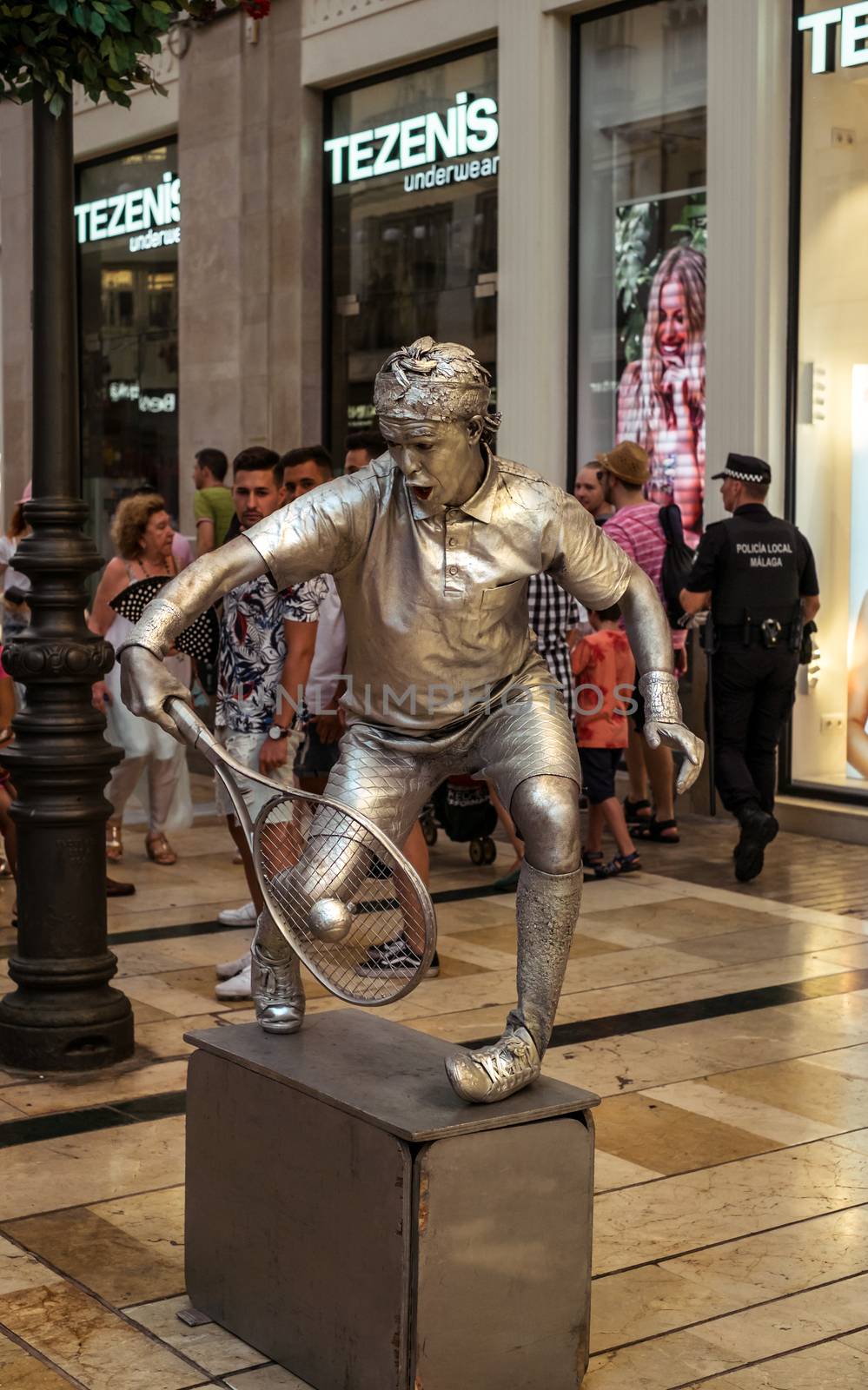 Malaga, Spain - August 14, 2018. Human statue of a tennis player performs on the Marques de Larios pedestrian, in the historic center of Malaga, Spain