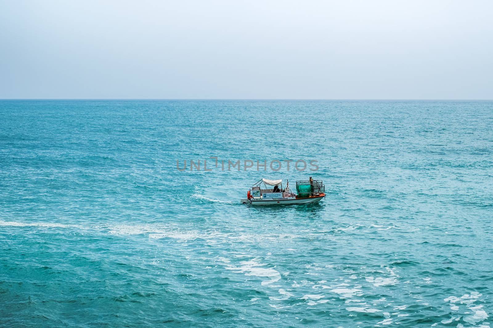 Malaga, Spain - April 21, 2018. Municipal ship for cleaning water and marine garbage on the route along the beach in Malaga city, Costa del sol, Spain