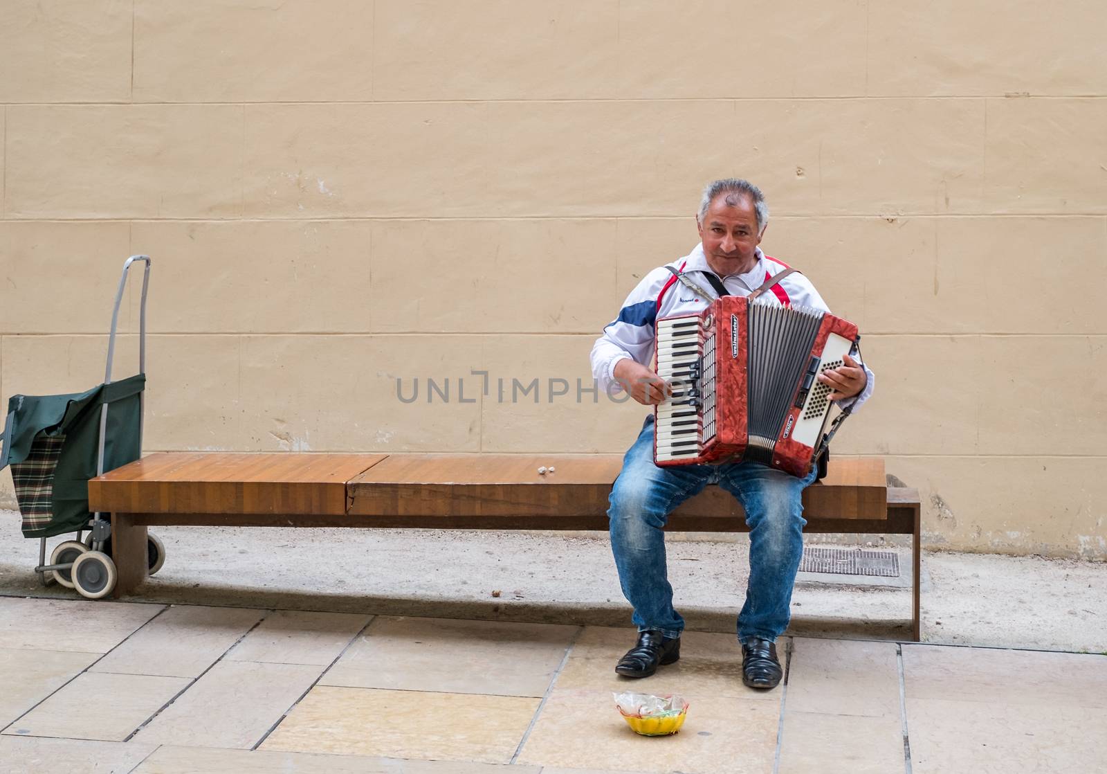 Malaga, Spain - April 10, 2018. Unidentified street musician playing melodies with his old accordion in Malaga city, Spain