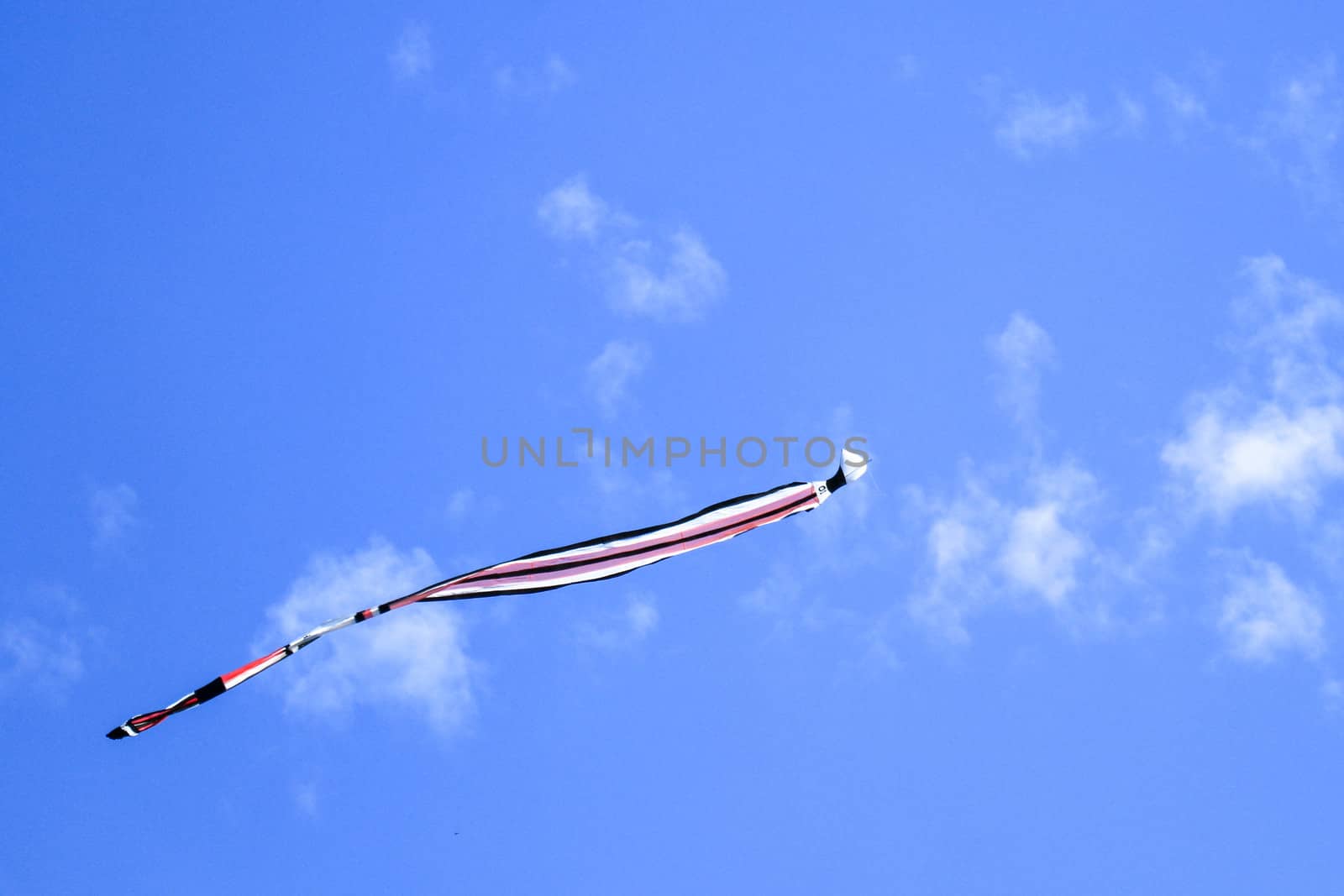 kite long tailfly on blue sky. The colorful kite on the blue sky with clouds. Space for text.