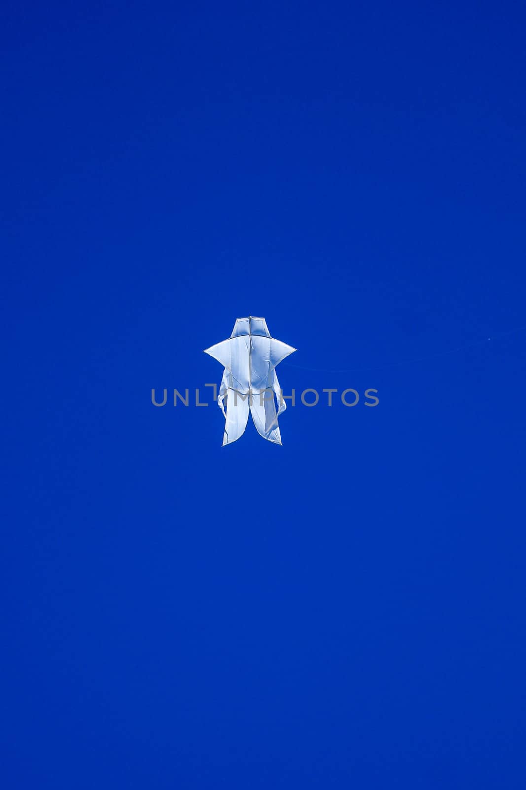 The Balinese white kite flies against the blue sky. Blue sky is the perfect background for kites. space for your text..