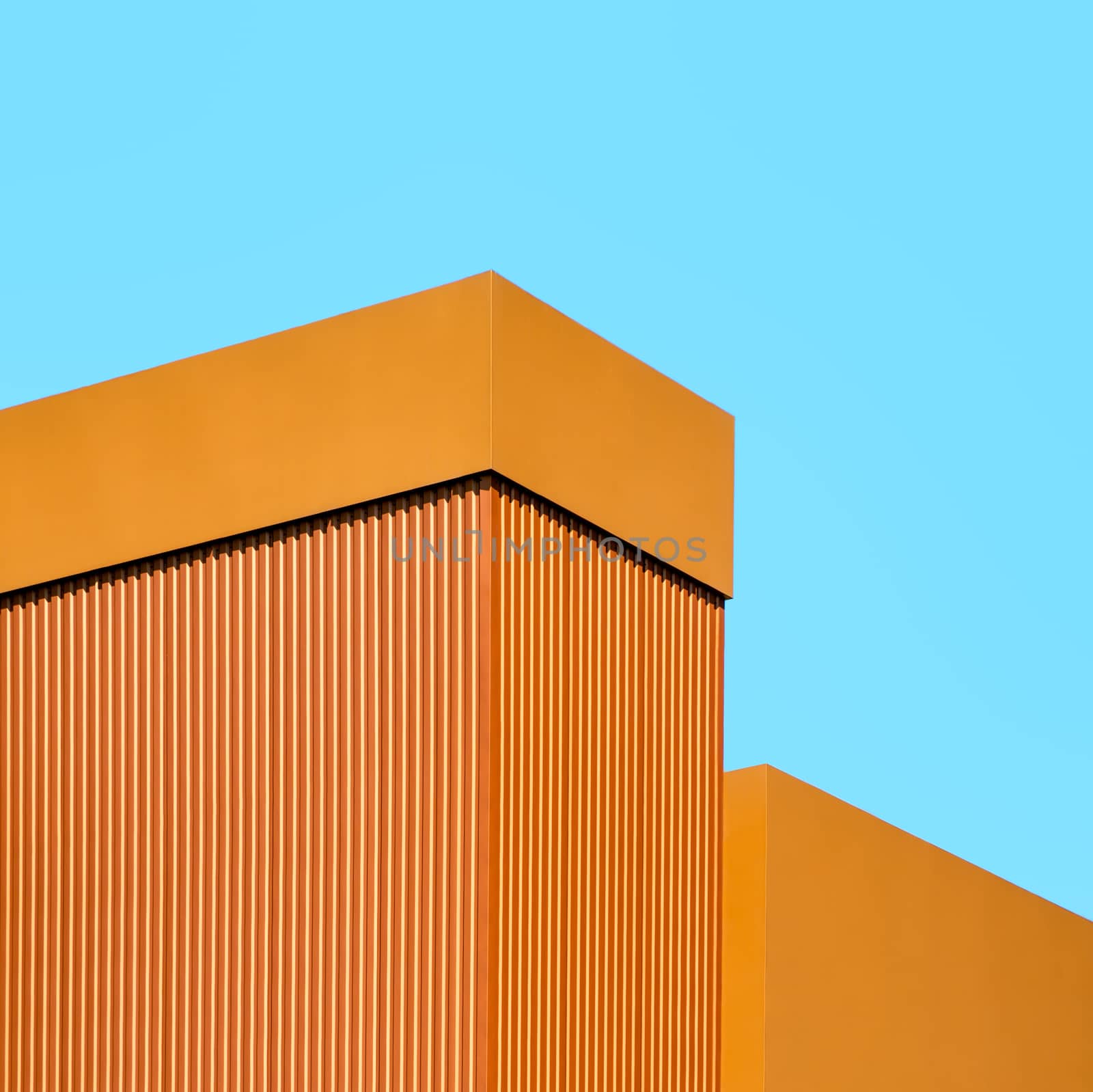 orange wall of a modern building on a background of blue sky simple architectural abstract background pattern