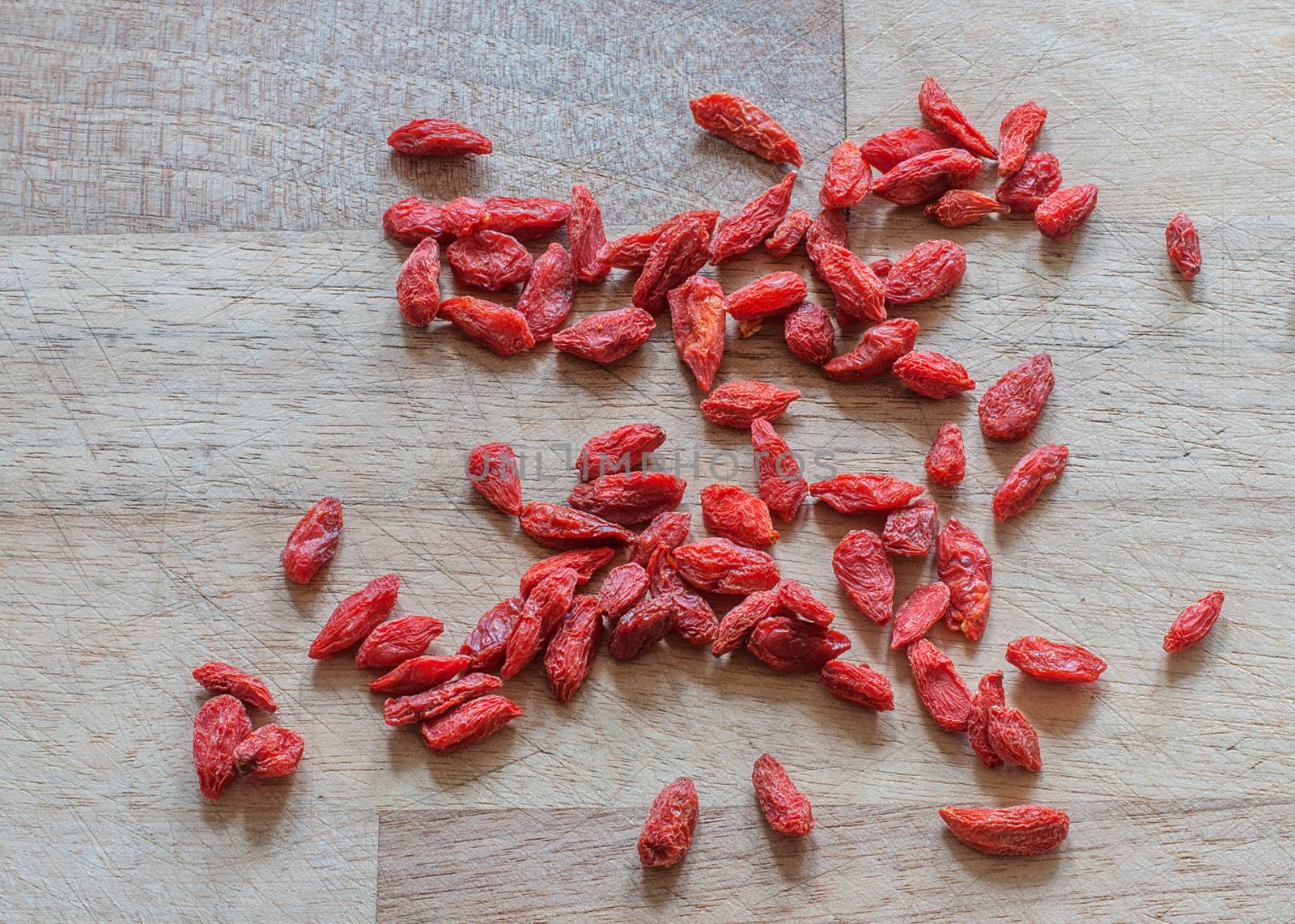 red goji berries on a wodden surface by sirspread