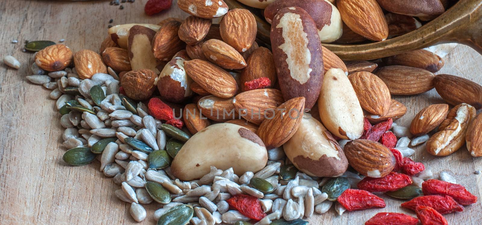 nuts goji berries and seeds on a wooden top by sirspread