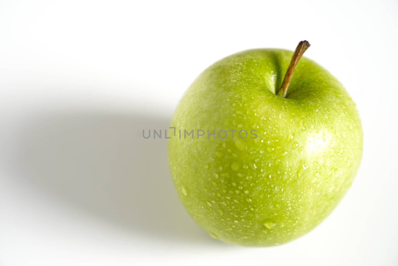 A whole granny smith green apple against a plain whit background