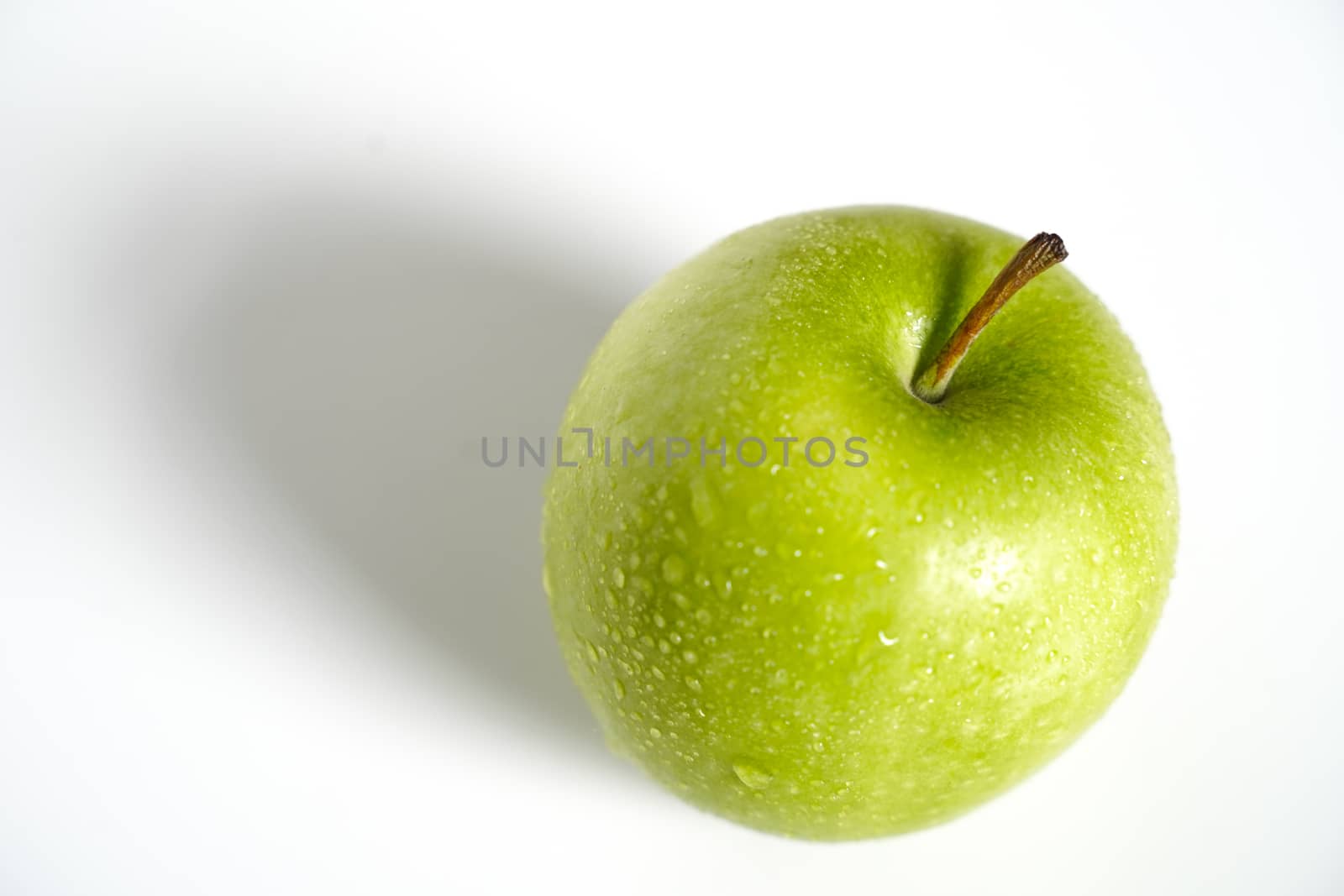 A whole granny smith green apple against a plain whit background