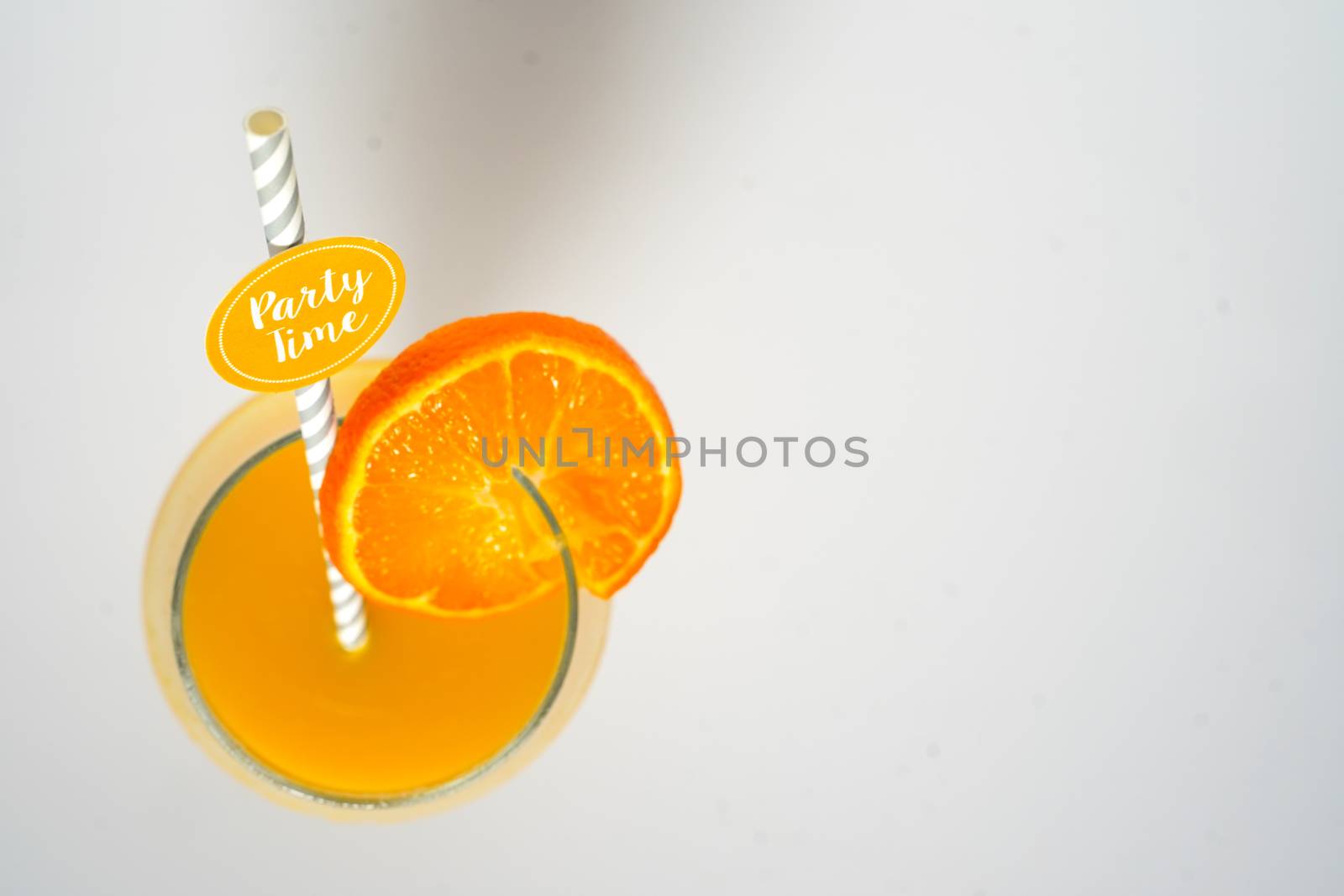 An orange cocktail drink with a party straw against a plain white background