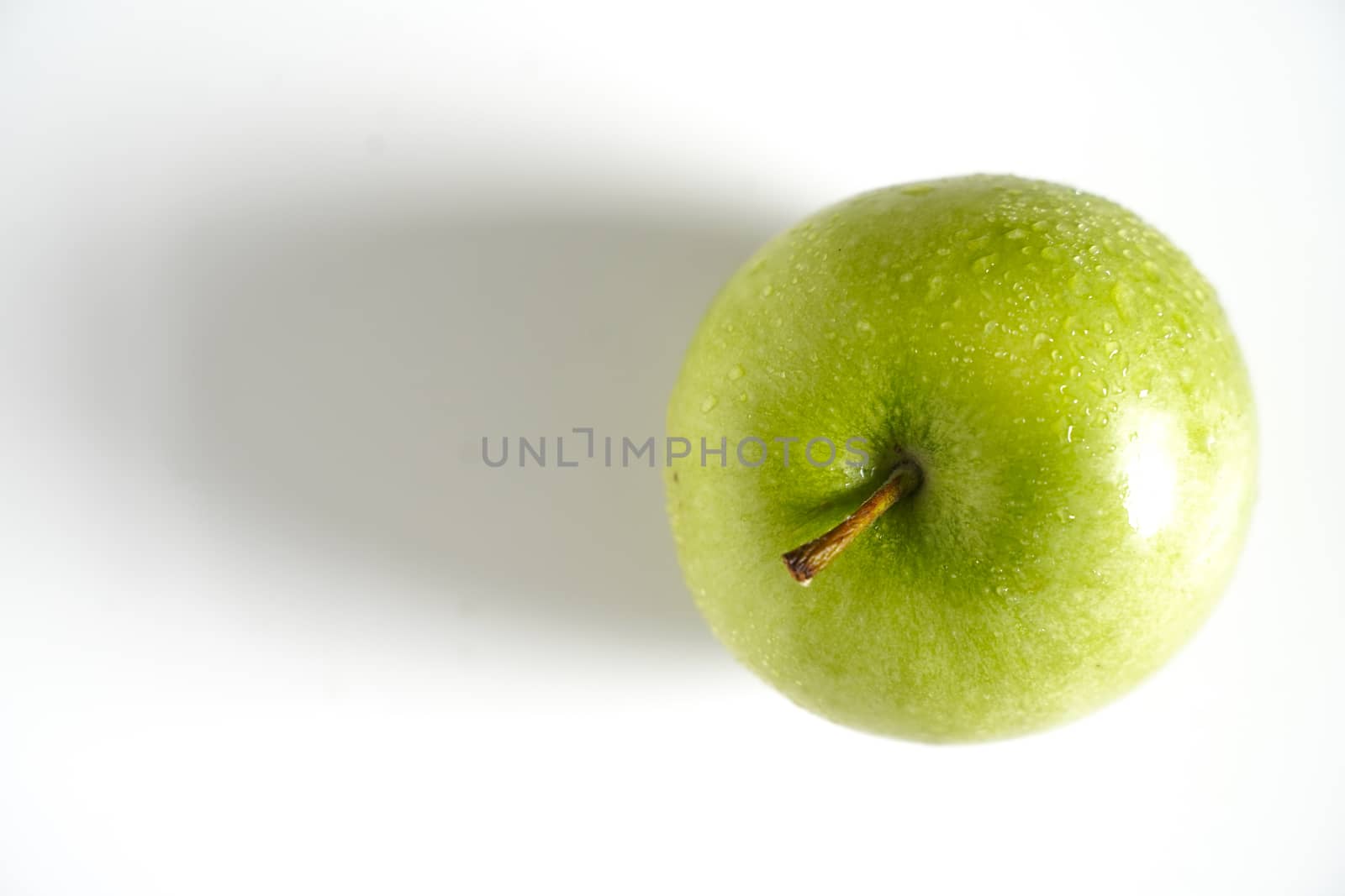A whole granny smith green apple against a plain whit background