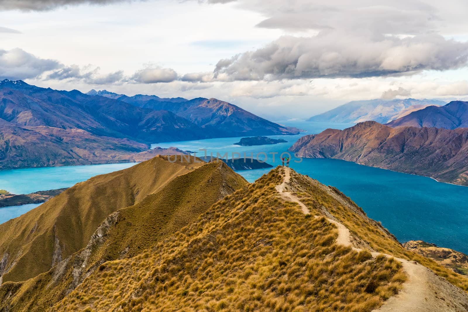 New Zealand hiking people on mountain top Roys Peak enjoying active outdoor lifestyle arms raised cheering happy in New Zealand nature landscape, near Wanaka, Otago, South Island, New Zealand.