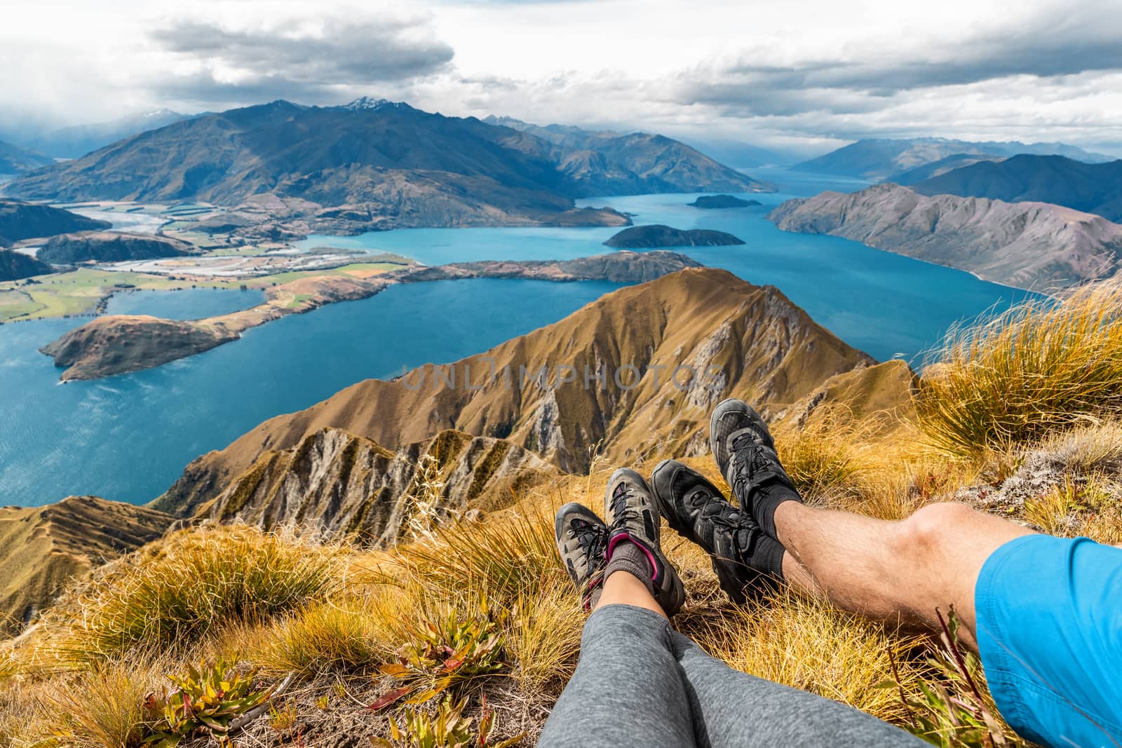 Wanderlust adventure and hiking travel vacation concept with hikers hiking boots close up. Hiker couple tramping up famous hike to Roys Peak on South Island, New Zealand. Couple resting and relaxing by Maridav