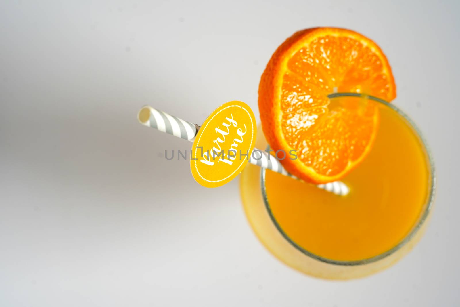 An orange cocktail drink with a party straw against a plain white background