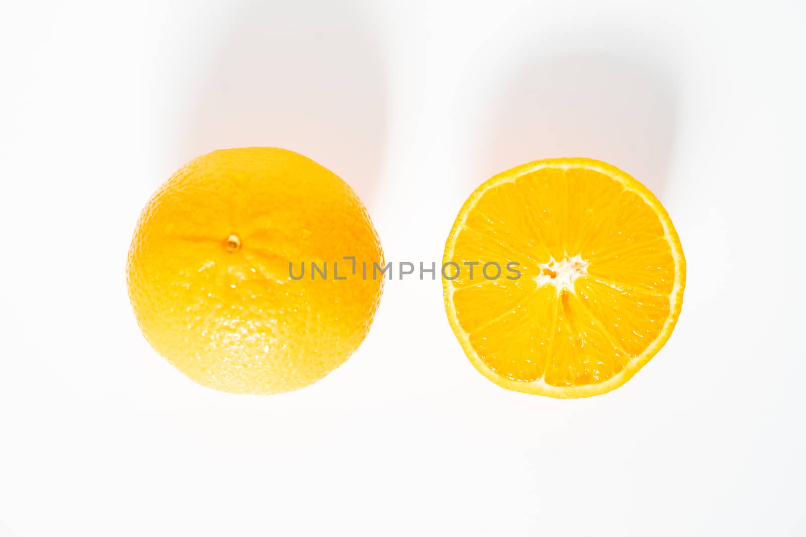 A whole orange and a half against a plain white background