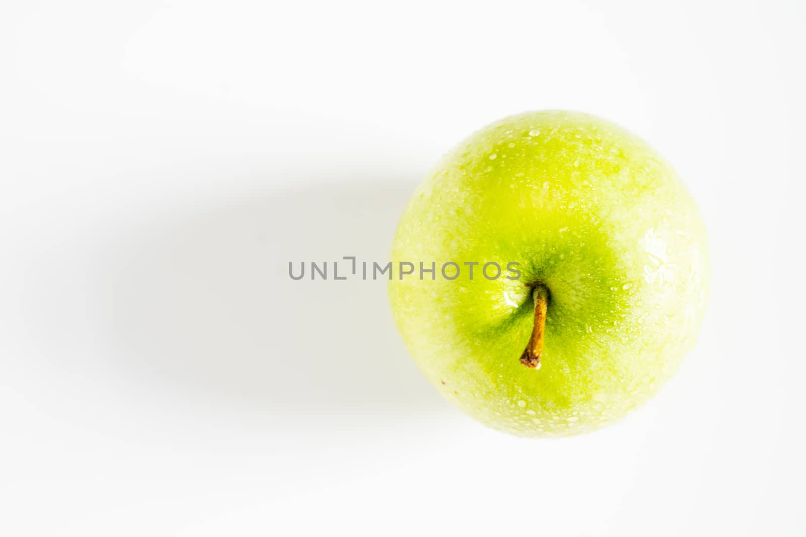 A whole granny smith green apple against a plain whit background