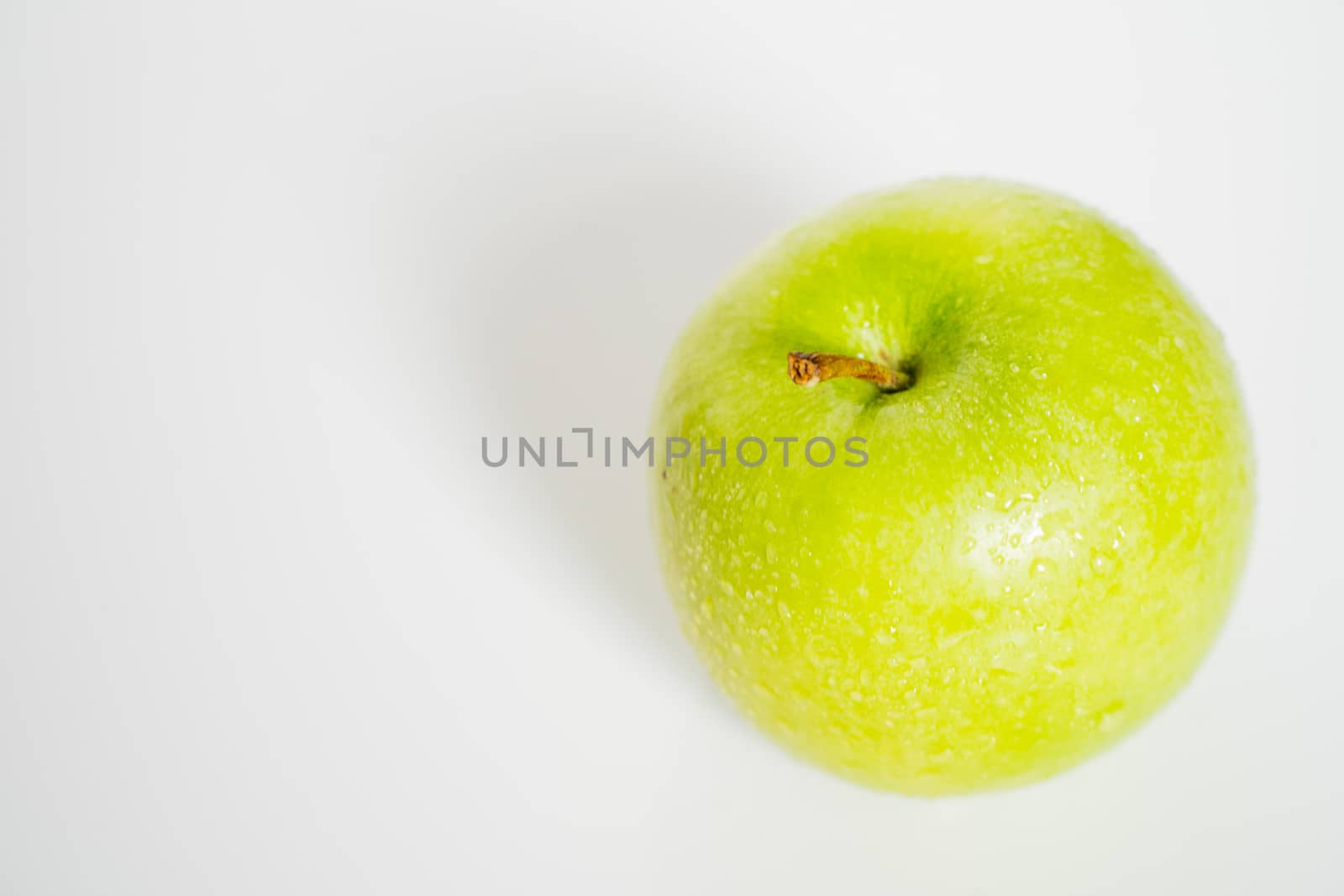 A whole granny smith green apple against a plain whit background