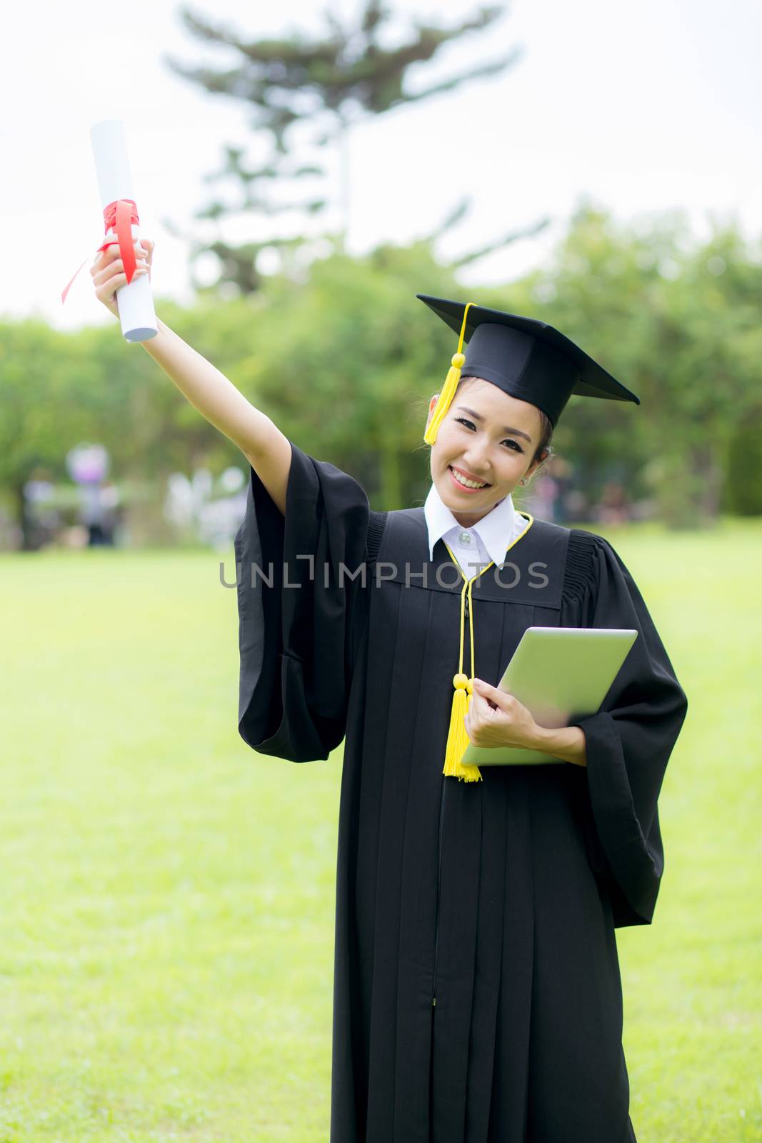 Graduate woman students wearing graduation hat and gown and hold by nnudoo